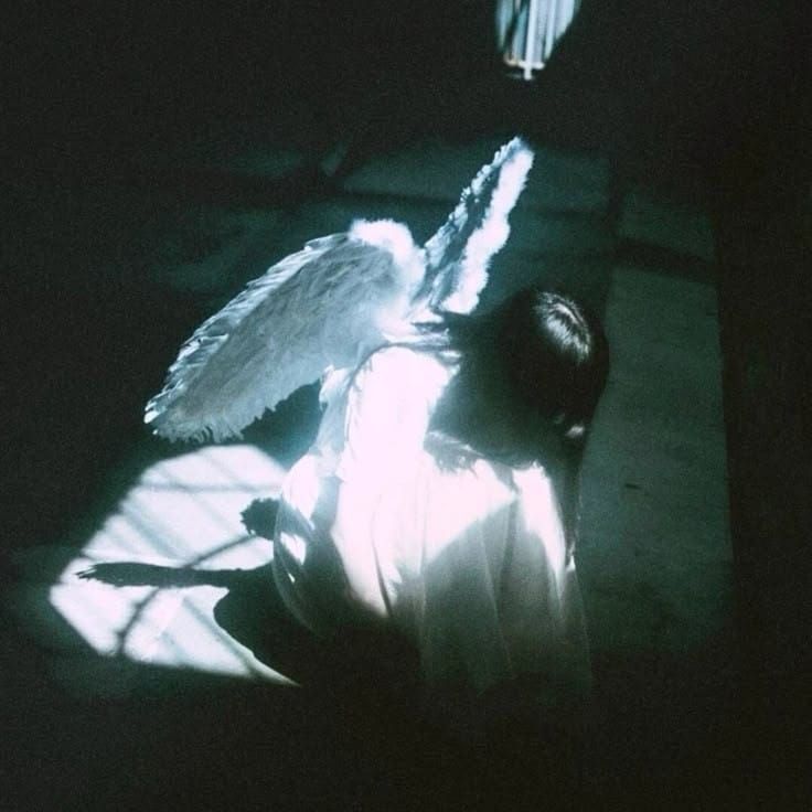 Praying Woman with Angel wings illuminated by a blue light.
